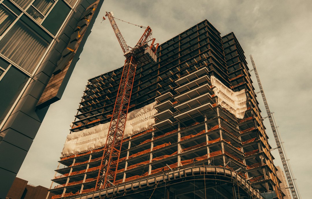 Grue rouge près d'un immeuble en construction, travaux poursuivis aux frais et risques du titulaire