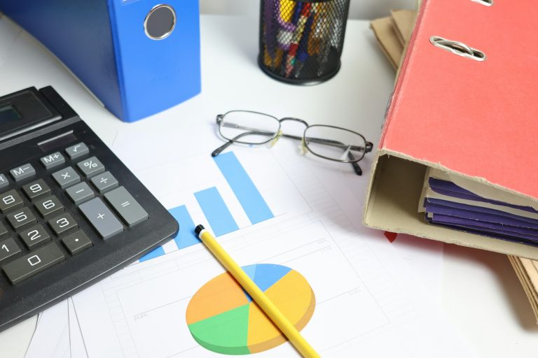 Actualisation des prix d'un marché public : calculatrice et tableaux de prix sur un bureau
