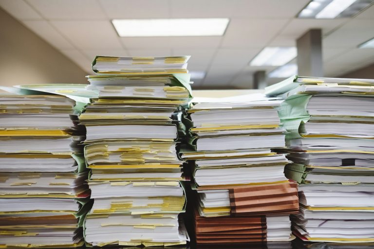 Pièces contractuelles contradictoires d'un marché public empilées sur un bureau